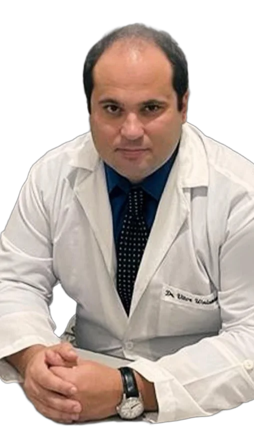 Dr. Vitor Waisman, ortopedista e traumatologista, de jaleco branco, sentado com as mãos apoiadas